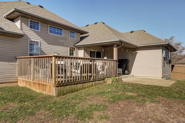 rear view of house featuring a wooden deck, a lawn, and a patio