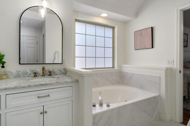 bathroom featuring tiled bath and vanity