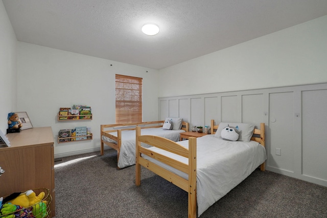 bedroom with a textured ceiling and dark carpet