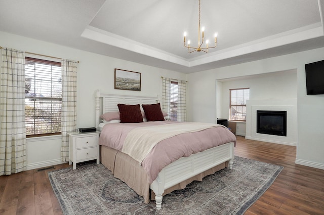 bedroom featuring dark wood-type flooring, a tray ceiling, and a chandelier