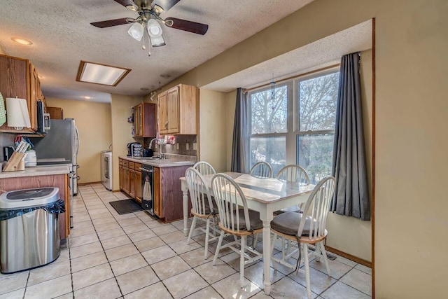 kitchen featuring washer / dryer, ceiling fan, black dishwasher, a textured ceiling, and sink