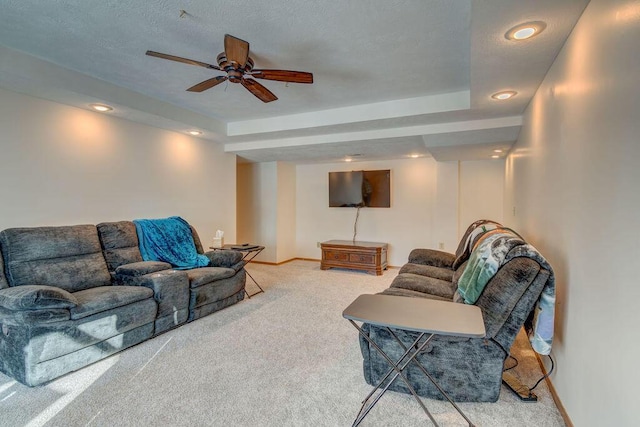 carpeted living room featuring ceiling fan and a raised ceiling