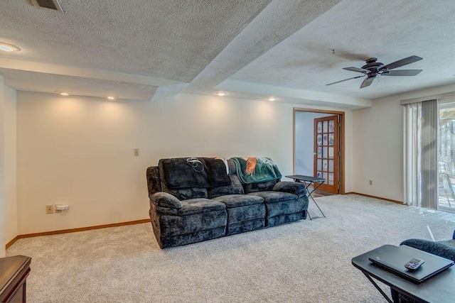 carpeted living room with ceiling fan and a textured ceiling