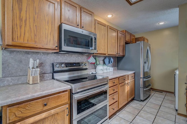 kitchen featuring decorative backsplash, a textured ceiling, light tile patterned floors, and stainless steel appliances