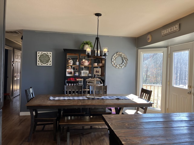 dining space featuring dark hardwood / wood-style flooring and an inviting chandelier