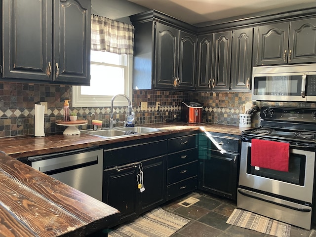 kitchen with appliances with stainless steel finishes, tasteful backsplash, butcher block countertops, and sink