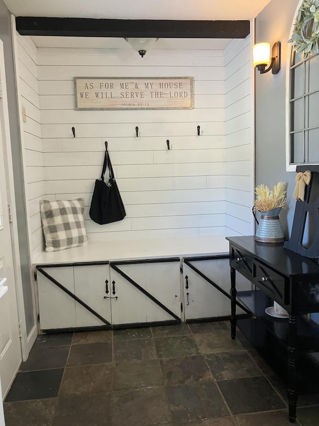 mudroom with beamed ceiling and wood walls