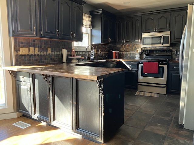 kitchen featuring tasteful backsplash, butcher block countertops, and stainless steel appliances