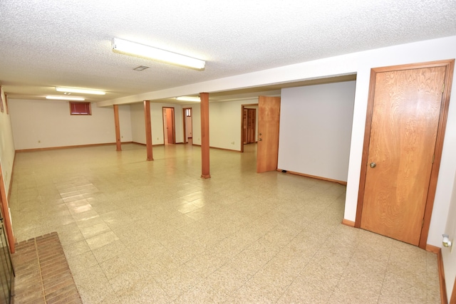 finished below grade area featuring baseboards, a textured ceiling, and light floors