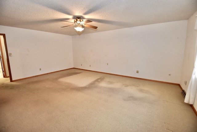 spare room with light carpet, ceiling fan, a textured ceiling, and baseboards