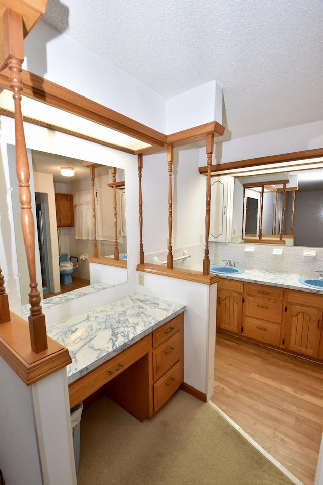 bathroom with tasteful backsplash, a sink, a textured ceiling, and double vanity