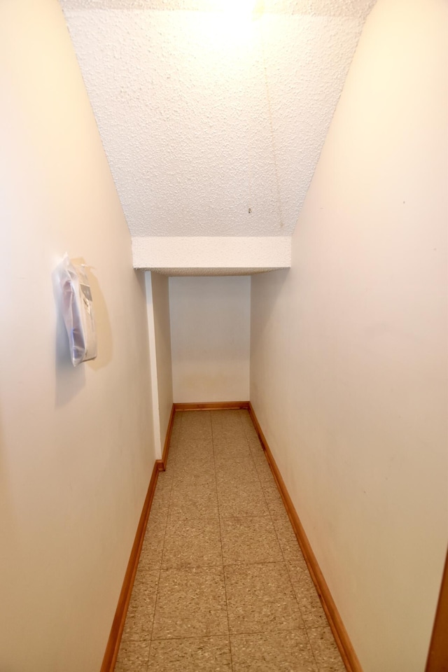 hall with lofted ceiling and baseboards