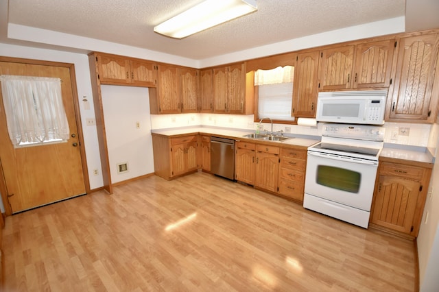 kitchen with white appliances, light wood finished floors, light countertops, a textured ceiling, and a sink