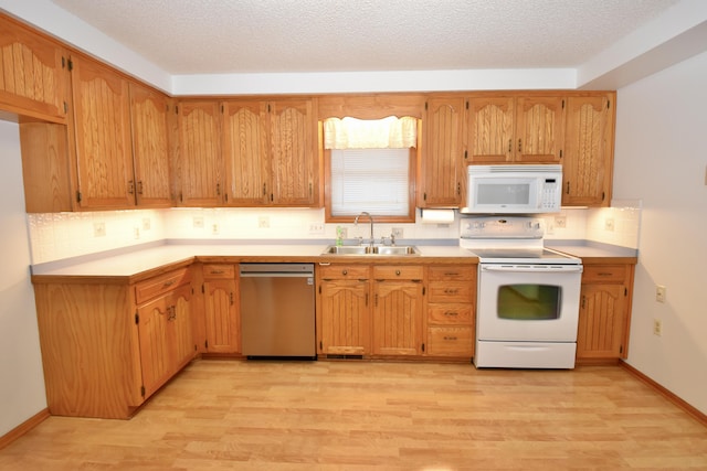 kitchen featuring decorative backsplash, light wood-style floors, a sink, a textured ceiling, and white appliances