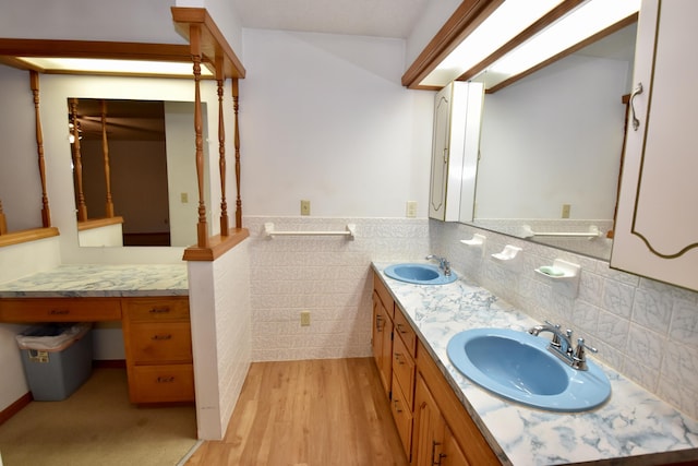 bathroom with wainscoting, a sink, tile walls, and wood finished floors