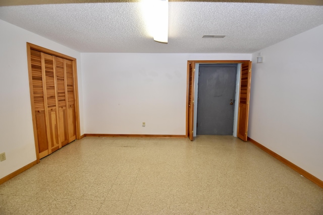 unfurnished room featuring light floors, baseboards, and a textured ceiling