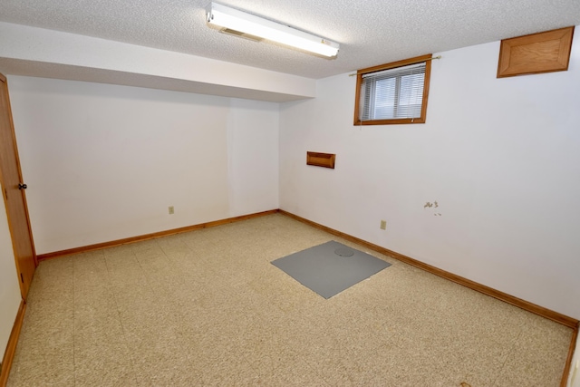 basement featuring visible vents, baseboards, and a textured ceiling