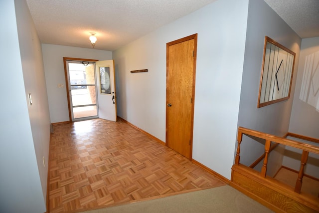 hall featuring a textured ceiling and baseboards