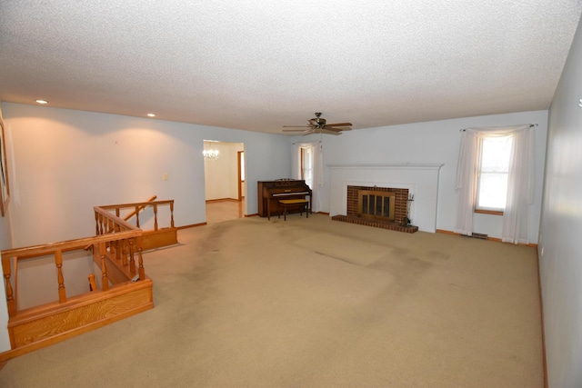 unfurnished living room with carpet, a brick fireplace, a textured ceiling, baseboards, and ceiling fan with notable chandelier