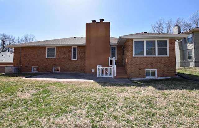 rear view of house featuring a chimney, a yard, a patio area, central AC, and brick siding