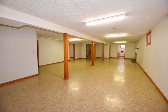 finished basement featuring light floors, stairs, baseboards, and a textured ceiling