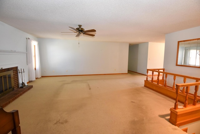 living room featuring baseboards, a ceiling fan, a textured ceiling, carpet floors, and a brick fireplace