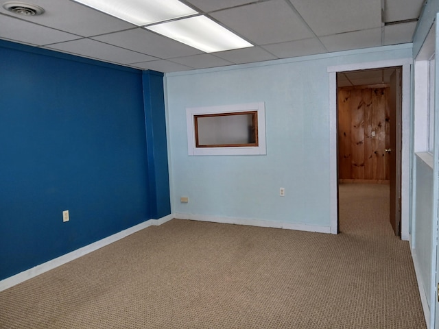 spare room featuring light carpet and a drop ceiling