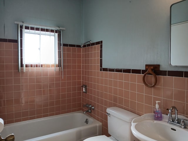 full bathroom featuring toilet, tile walls, tiled shower / bath, and sink