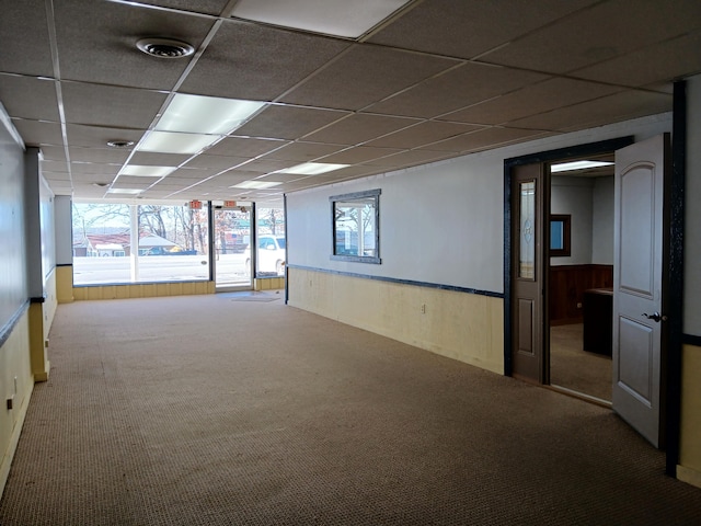 carpeted spare room with a drop ceiling