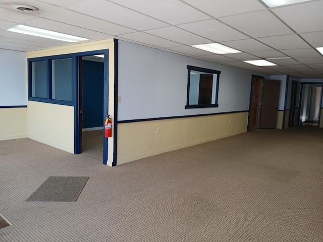 basement featuring light colored carpet and a drop ceiling