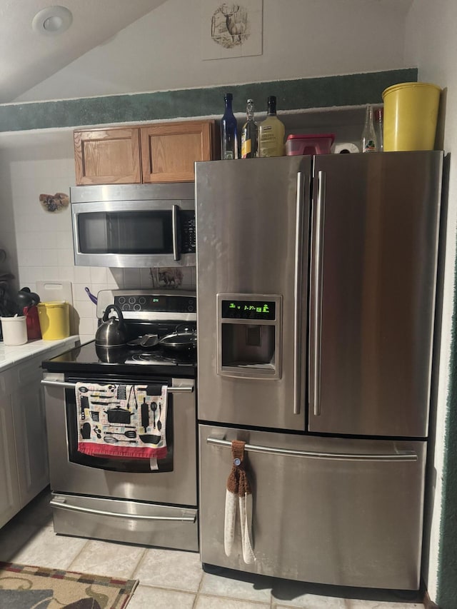 kitchen with light tile patterned flooring, stainless steel appliances, and lofted ceiling