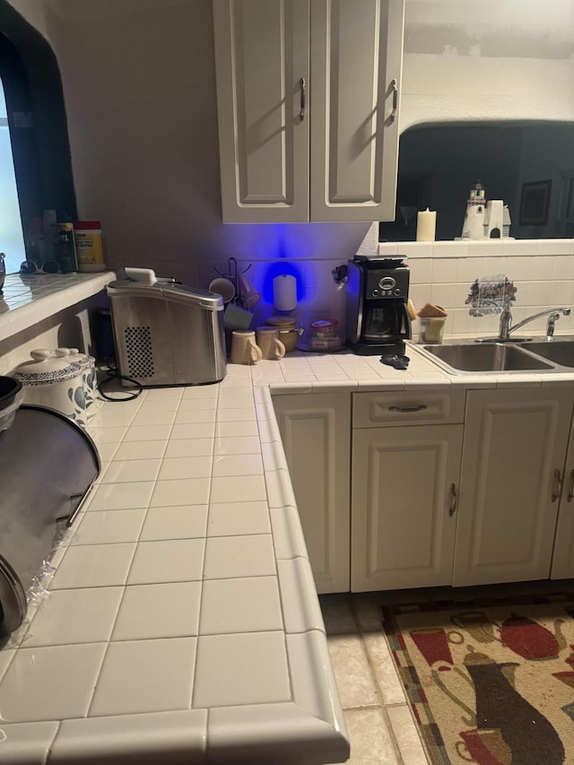 kitchen with gray cabinets, tile counters, decorative backsplash, and sink