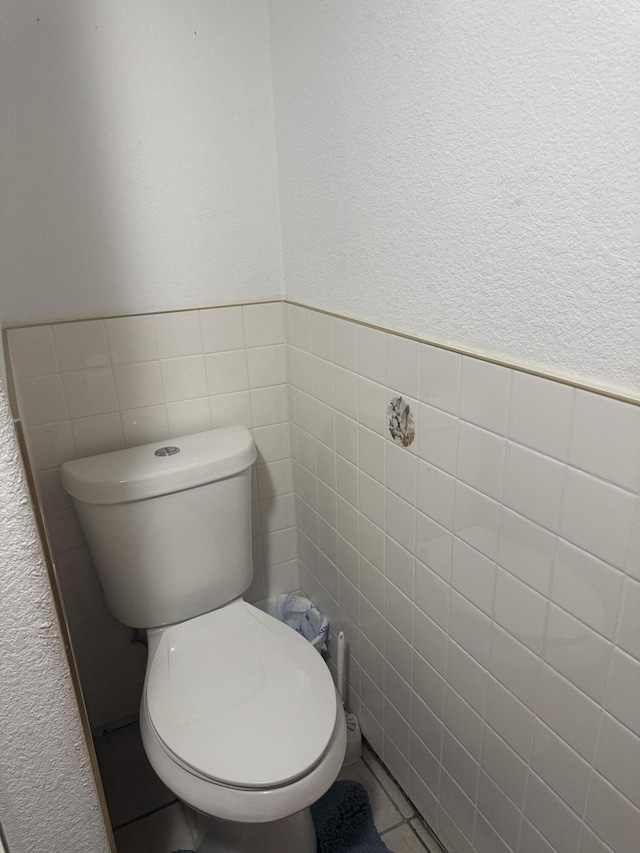 bathroom featuring toilet, tile walls, and tile patterned flooring