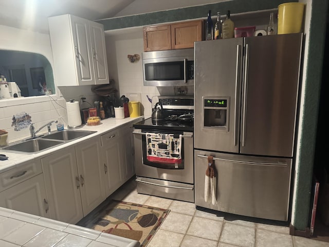 kitchen with white cabinetry, appliances with stainless steel finishes, decorative backsplash, tile counters, and sink