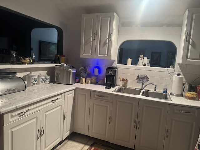 kitchen with white cabinetry, tile countertops, tasteful backsplash, and sink