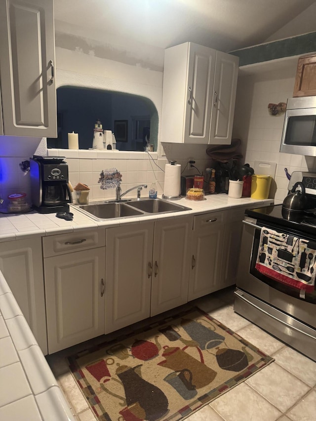 kitchen with stainless steel appliances, backsplash, tile counters, and gray cabinets