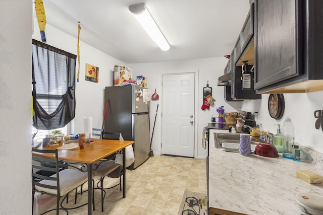 kitchen featuring a textured ceiling, sink, and stainless steel refrigerator