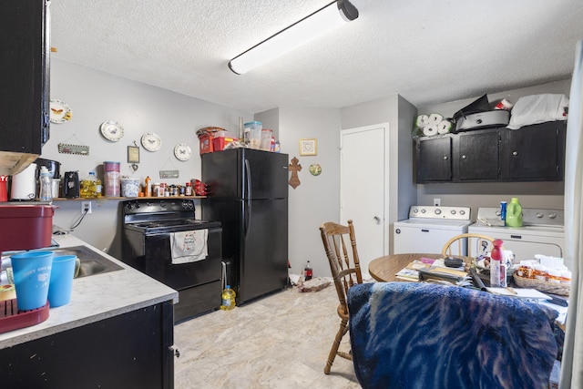 kitchen with a textured ceiling, sink, washing machine and clothes dryer, and black appliances