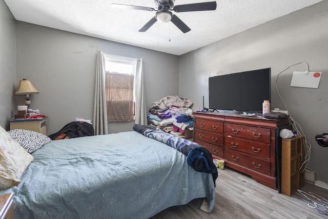 bedroom with ceiling fan, a textured ceiling, and light hardwood / wood-style floors