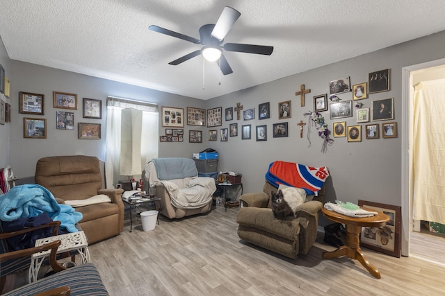 living room featuring ceiling fan, a textured ceiling, and light hardwood / wood-style floors