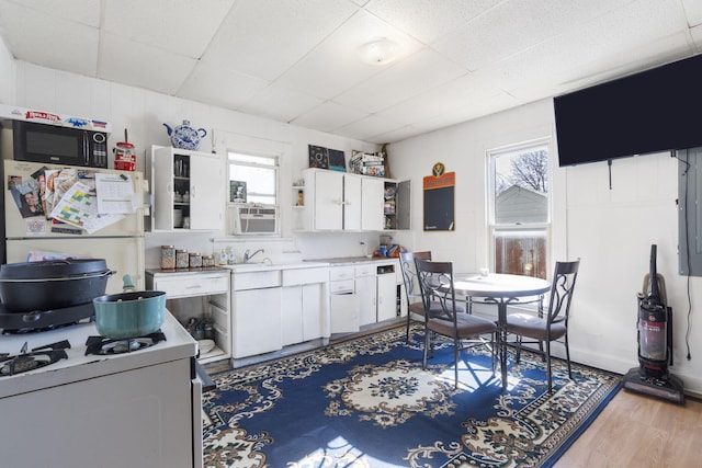 kitchen with sink, a wealth of natural light, white cabinets, and light hardwood / wood-style flooring