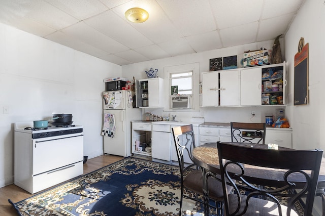 kitchen featuring hardwood / wood-style flooring, white appliances, white cabinets, and a paneled ceiling