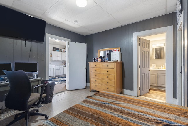 home office with a drop ceiling and wood walls