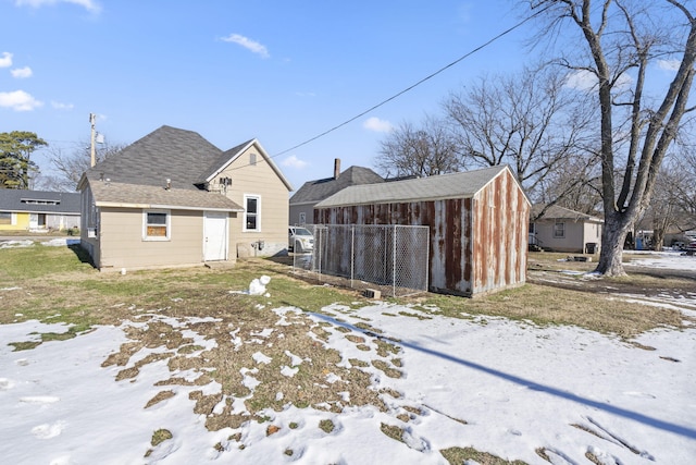 snow covered back of property featuring an outbuilding