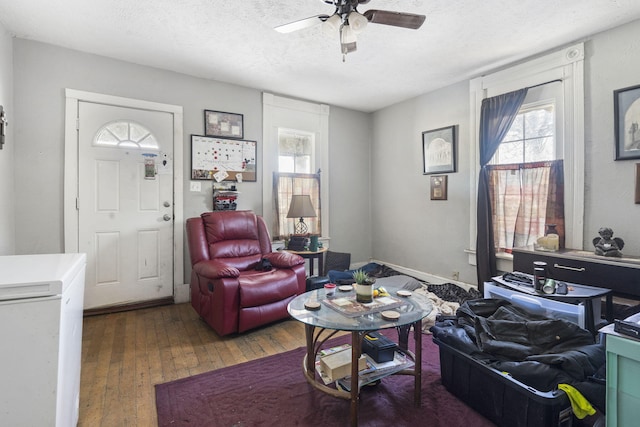 living room featuring a textured ceiling, ceiling fan, and dark hardwood / wood-style floors