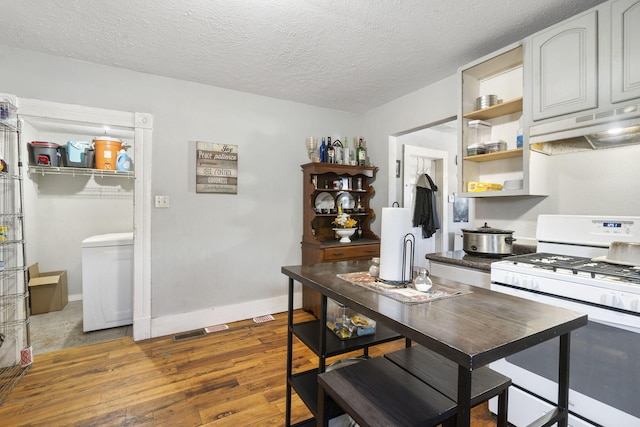 kitchen featuring a textured ceiling, white cabinetry, white gas range, and dark hardwood / wood-style floors