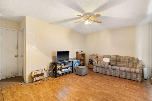 living room with ceiling fan, wood-type flooring, and a textured ceiling