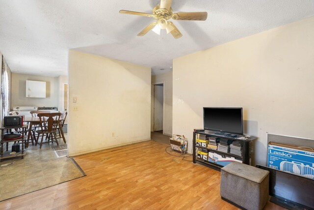 living room featuring ceiling fan, a textured ceiling, and light hardwood / wood-style flooring