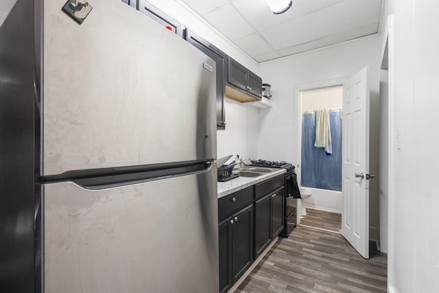 kitchen with dark hardwood / wood-style floors, a paneled ceiling, gas stove, and stainless steel refrigerator