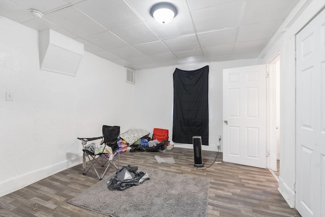 interior space with a paneled ceiling and dark hardwood / wood-style floors